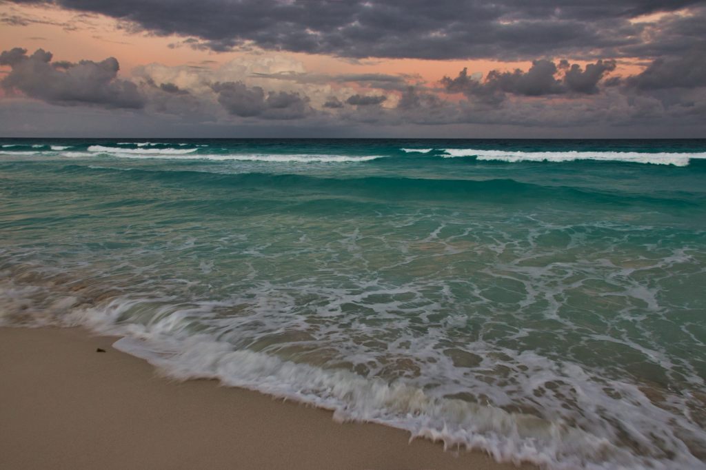 Dark clouds with a glowing orange sky over the water off the coast of Cancun.